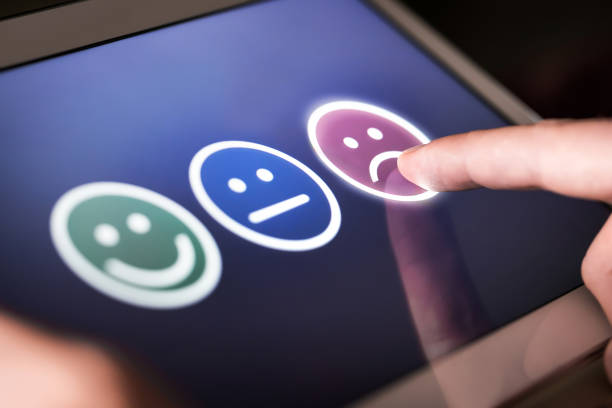 Finger wählt trauriges Gesicht auf Touchscreen mit drei Gesichtern für Feedback