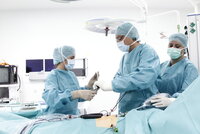 Chirurgen in Operationssaal führen minimalinvasive Operation durch, Patient liegt auf OP-Tisch